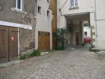 Cours avec des pavés, des portes de garage et au fond une arche menant à une seconde cour